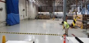 Applicators of Epoxy Flooring Brisbane spreading epoxy paint on industrial warehouse 